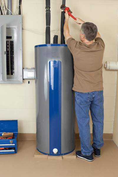 technician tightens pipe during water heater repair job