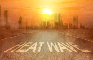 An outline of a city in the distance with a fiery orange sky and the words HEAT WAVE written on the ground close to the bottom.